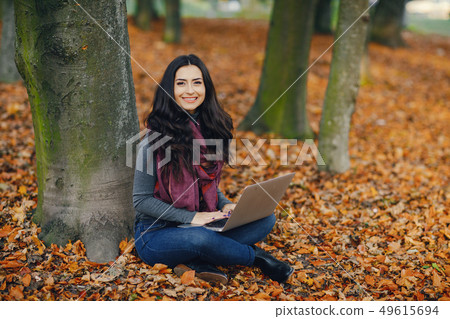 brunette girl working on her laptop in the park 49615694