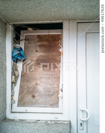 Boarded up window next to door of a house Boarded up window next to door of a house 49617626