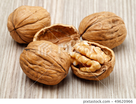 Whole and cracked walnuts on wooden board 49620966