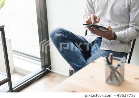young asian man using pad tablet mobile device at a workplace - young asian man using pad tablet mobile device at a workplace - 49627752