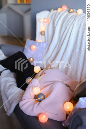 Pregnant woman lying on sofa near garlands. 49634350