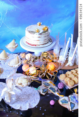 Birthday cake and sweets in blue background, garlands on table. 49634514