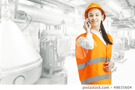 Destroying gender stereotypes. Female builder standing against industrial background Destroying gender stereotypes. Female builder standing against industrial background 49635604