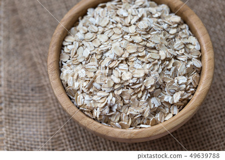 Uncooked oatmeal or oat flakes in a wooden bowl Uncooked oatmeal or oat flakes in a wooden bowl 49639788