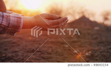 A farmer looks at the soil in his hands at sunset. A farmer looks at the soil in his hands at sunset. 49643154