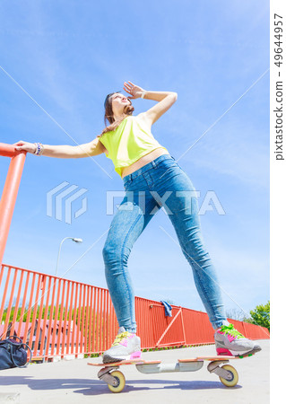 Teen girl skater riding skateboard on street. Teen girl skater riding skateboard on street. 49644957