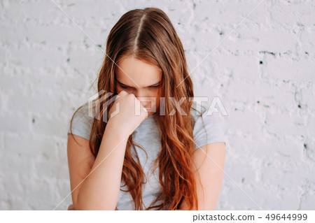 Sad teen girl with long curly red hair isolated Sad teen girl with long curly red hair isolated 49644999
