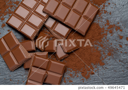 Dark or milk organic chocolate pieces and cocoa powder on dark concrete backgound 49645471