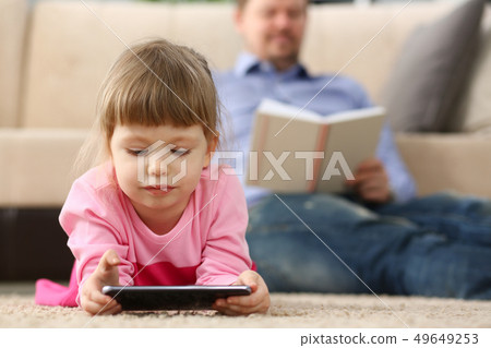 Father and daughter lie on floor using mobile phone 49649253
