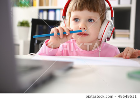 Little girl wearing headphones use mobile computer Little girl wearing headphones use mobile computer 49649611
