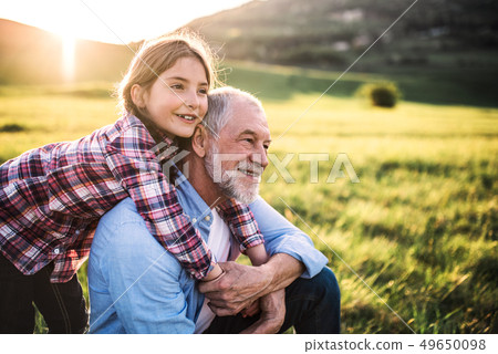 A small girl with grandfather outside in spring nature, relaxing on the grass. 49650098