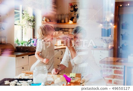 Senior grandmother with small toddler boy making cakes at home. 49650127