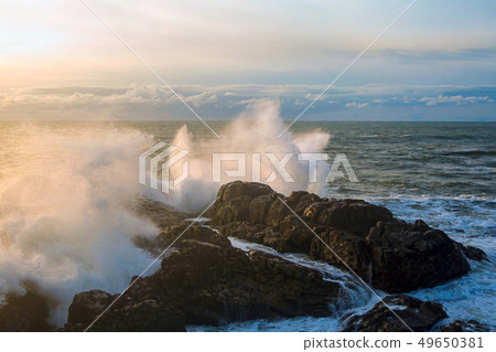 Waves of the Atlantic Ocean crashing against a rock at sunset. Waves of the Atlantic Ocean crashing against a rock at sunset. 49650381