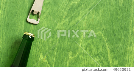 Beer bottle and opener on the green table Beer bottle and opener on the green table 49650931