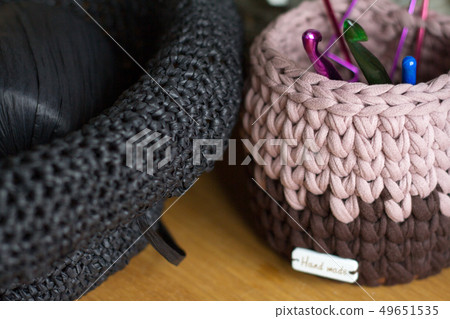 Two-tone knitted basket on a light wooden surface Two-tone knitted basket on a light wooden surface 49651535