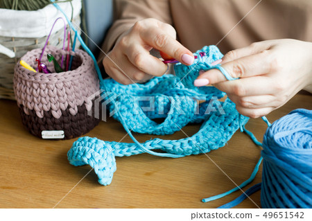 Hands of a young woman knit crochet from blue yarn Hands of a young woman knit crochet from blue yarn 49651542