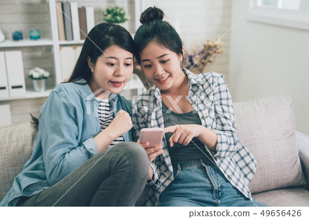 girls sharing earphones pointing show cellphone 49656426