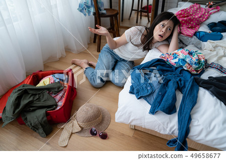Upset girl trying to pack clothes in suitcase Upset girl trying to pack clothes in suitcase 49658677