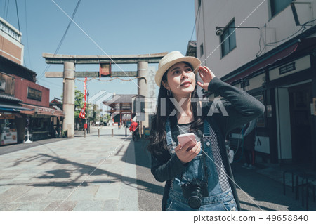 Happy woman walking in street using smartphone 49658840