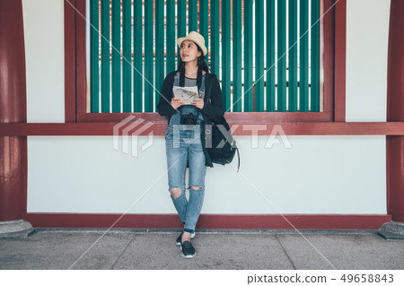 traveler standing on wall with paper map traveler standing on wall with paper map 49658843