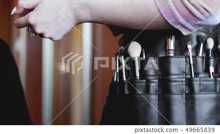 Professional make-up artist with a belt bag with tassels. makeup brushes Professional make-up artist with a belt bag with tassels. makeup brushes 49665839