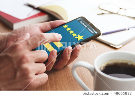 Up of a male hand sending stars 5 reviews on a smartphone. 49665952