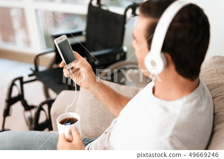 Man Listens to Music in Headphones and Drinks Tea Man Listens to Music in Headphones and Drinks Tea 49669246
