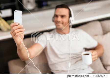 Man Makes Selfie in Headphones while Drink Coffee Man Makes Selfie in Headphones while Drink Coffee 49669248