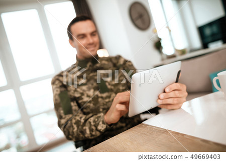 Smiling Military Man Uses Tablet in Living Room Smiling Military Man Uses Tablet in Living Room 49669403