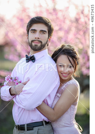 Newlyweds in love stand on the nature, against the background of wooden stakes, in sunny weather 49673435