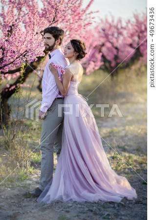 Beautiful wedding couple in the gardens of a blossoming peach. 49673436