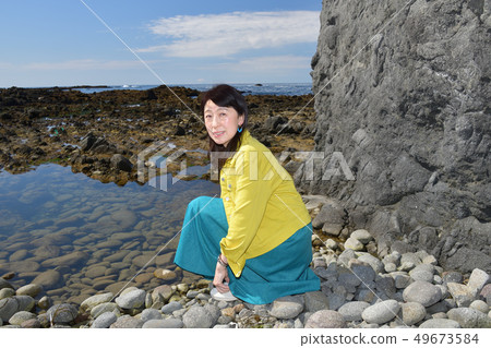 在北海道伊勢那市市長海岸伊勢那市市長的海岸上拍攝了一個穿著黃色夾克和藍色裙子的黑髮女子肖像 在北海道伊勢那市市長海岸伊勢那市市長的海岸上拍攝了一個穿著黃色夾克和藍色裙子的黑髮女子肖像 49673584