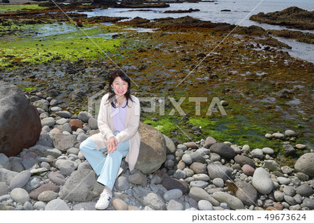 一名婦女的射擊畫像有黑髮的棲息在市長Isotana,Setana,北海道的一塊岩石 一名婦女的射擊畫像有黑髮的棲息在市長Isotana,Setana,北海道的一塊岩石 49673624