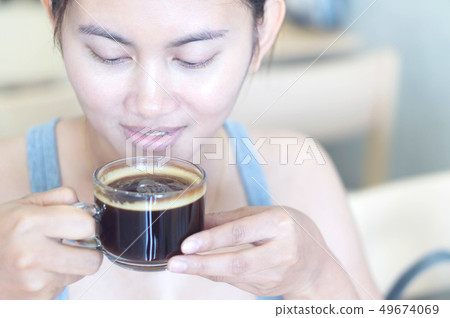 Closeup woman hand holding glass of hot americano Closeup woman hand holding glass of hot americano 49674069