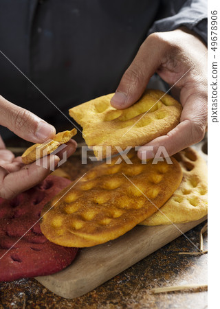 man splitting a piece of an italian focaccia. 49678906