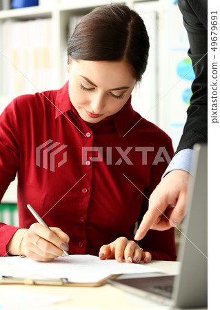 Female worker making notes in documents where male boss arm showing 49679691