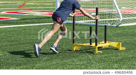 Athlete pushing yellow sled across green turf Athlete pushing yellow sled across green turf 49680406