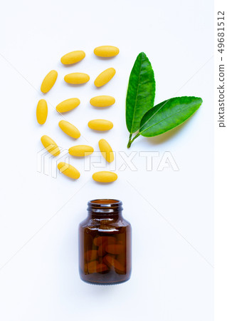 Vitamin C bottle and pills with  green leaves on 49681512
