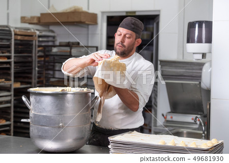 Pastry Chef with confectionary bag squeezing cream at pastry shop. 49681930