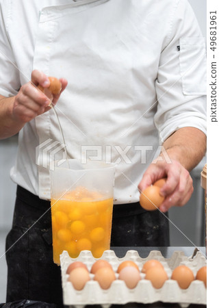 Pastry Chef breaking eggs to prepare the cake 49681961