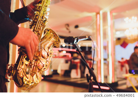 Golden saxophone in the hands of a musician near the microphone. 49684001