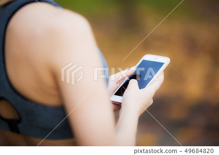 Woman Listening Music On Phone While Exercising Outdoors Woman Listening Music On Phone While Exercising Outdoors 49684820