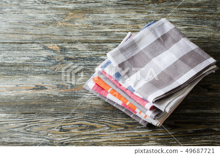 Stack of kitchen towels or napkins over the rustic wooden table. 49687721