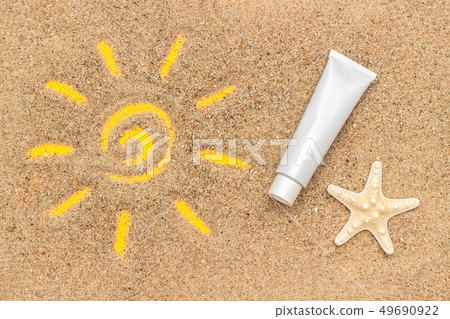 Sun sign drawn on sand, starfish and white tube of 49690922