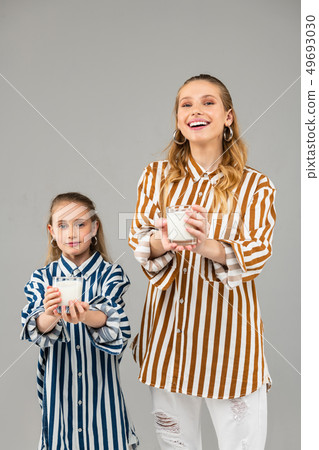 Cheerful long-haired sisters standing on grey background Cheerful long-haired sisters standing on grey background 49693030