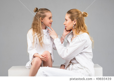 Long-haired good-looking sisters in white outfits gently touching each other 49693439