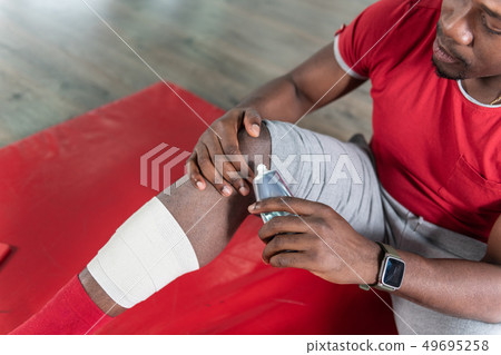 Attentive upset young man dealing with trauma during sportive training Attentive upset young man dealing with trauma during sportive training 49695258
