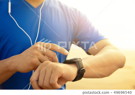 young Man running on beach and checking Heart Rate 49696540