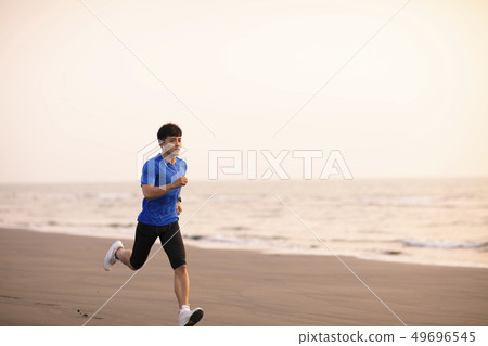 young Man running on  beach at sunset 49696545