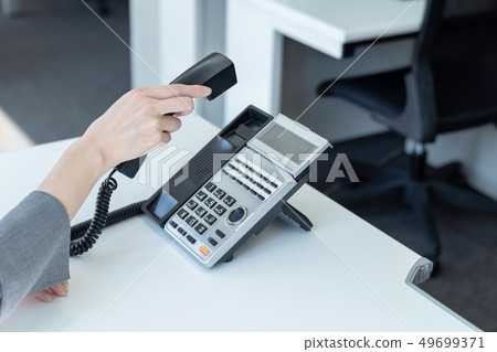 A woman taking a telephone receiver A woman taking a telephone receiver 49699371